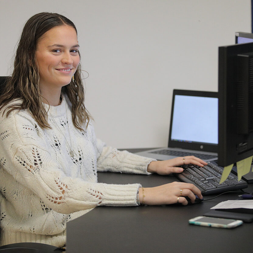 Kvindelig IT-supporter sidder ved computer og smiler