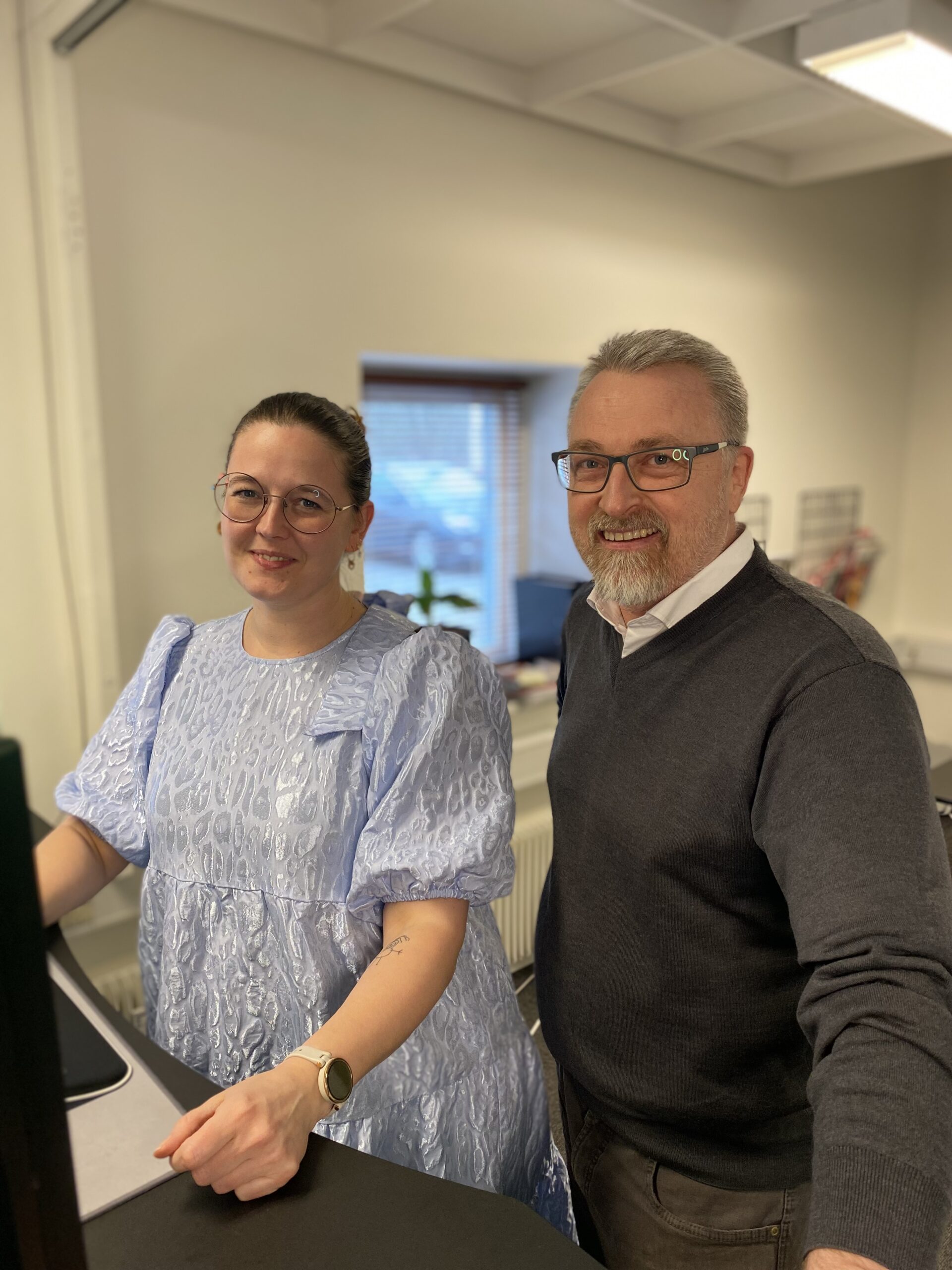 To Azend-medarbejdere i samarbejde foran en computerskærm på kontoret, der illustrerer teamwork og professionalisme.
