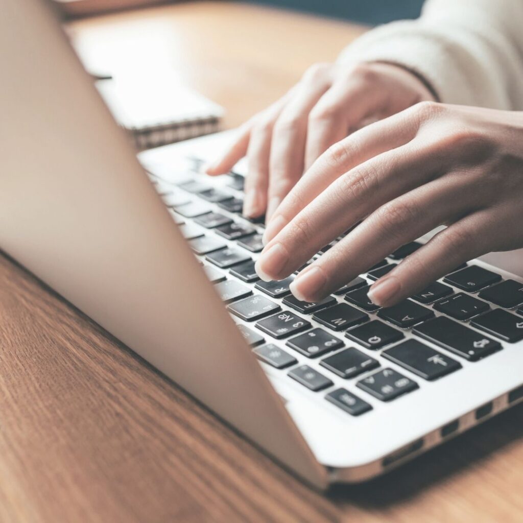 Hænder, der skriver på en laptop, symboliserer arbejde med forebyggelse af databrud og datasikkerhed.