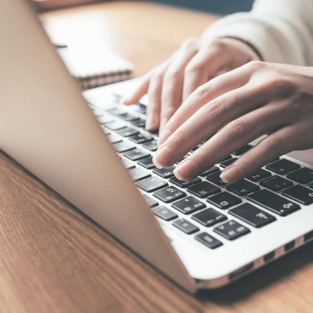 Hænder, der skriver på en laptop, symboliserer arbejde med forebyggelse af databrud og datasikkerhed.