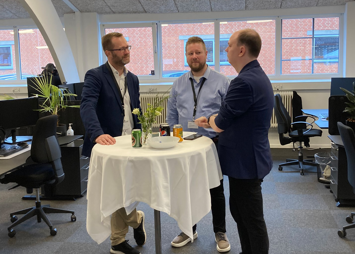Ejerkredsen hos Azend står samlet ved et bord og diskuterer strategier i en uformel atmosfære.