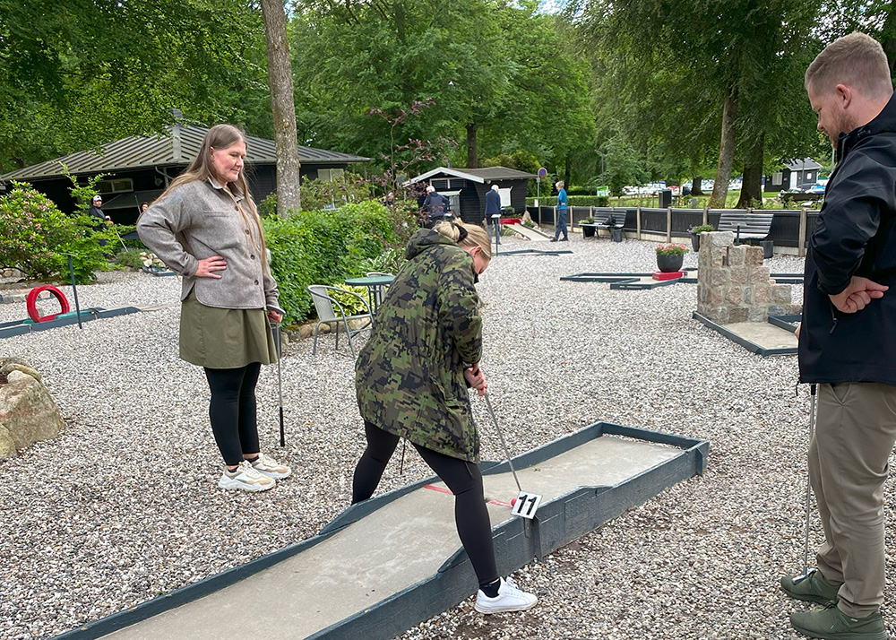 Azend-medarbejdere spiller minigolf under en social aktivitet, der styrker kollegaskab og fællesskab.