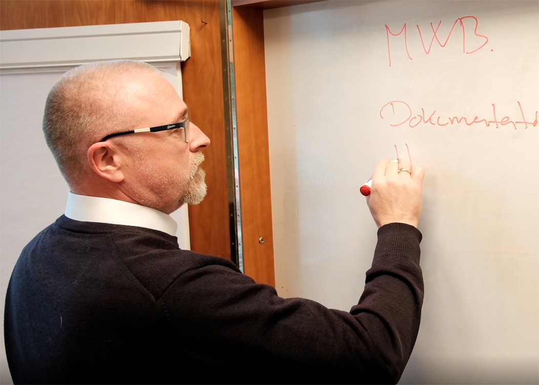 En Azend-medarbejder underviser ved en whiteboard-session, der fremhæver virksomhedens fokus på læring og udvikling.